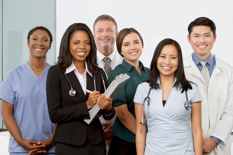 A group of diverse medical professionals stand together, smiling at the camera.